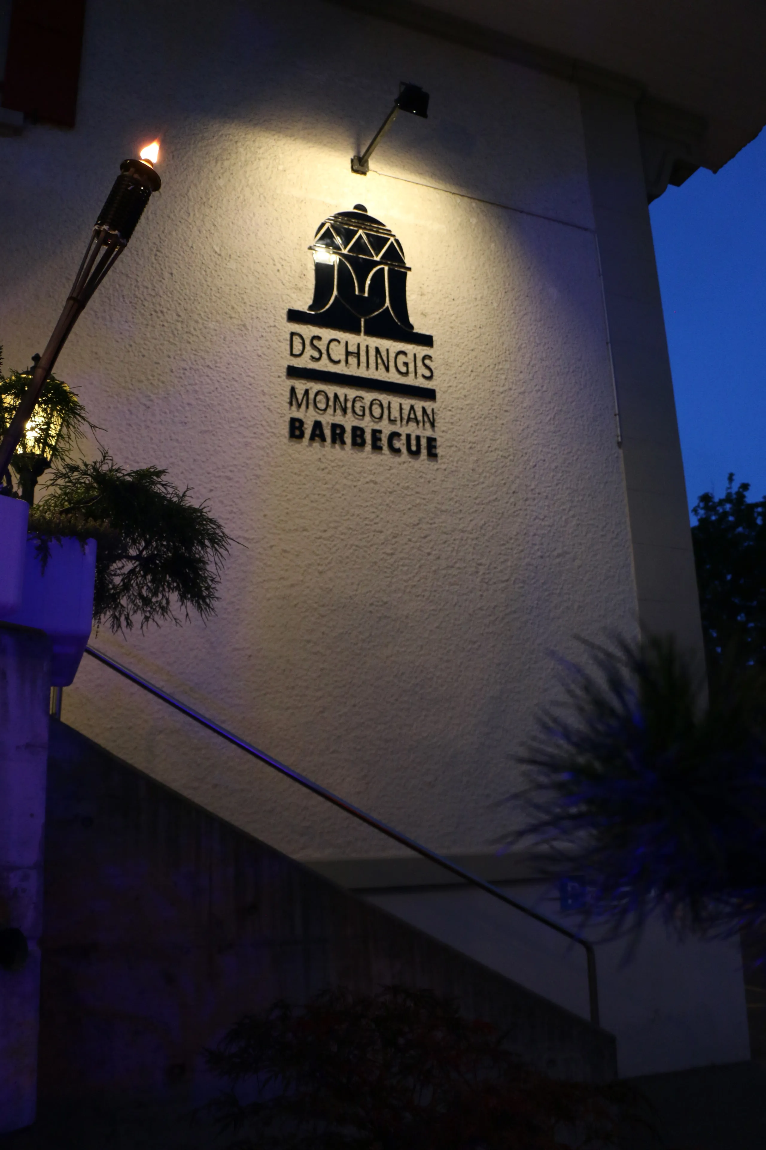 Beleuchteter Schriftzug am Eingang bei Dämmerung