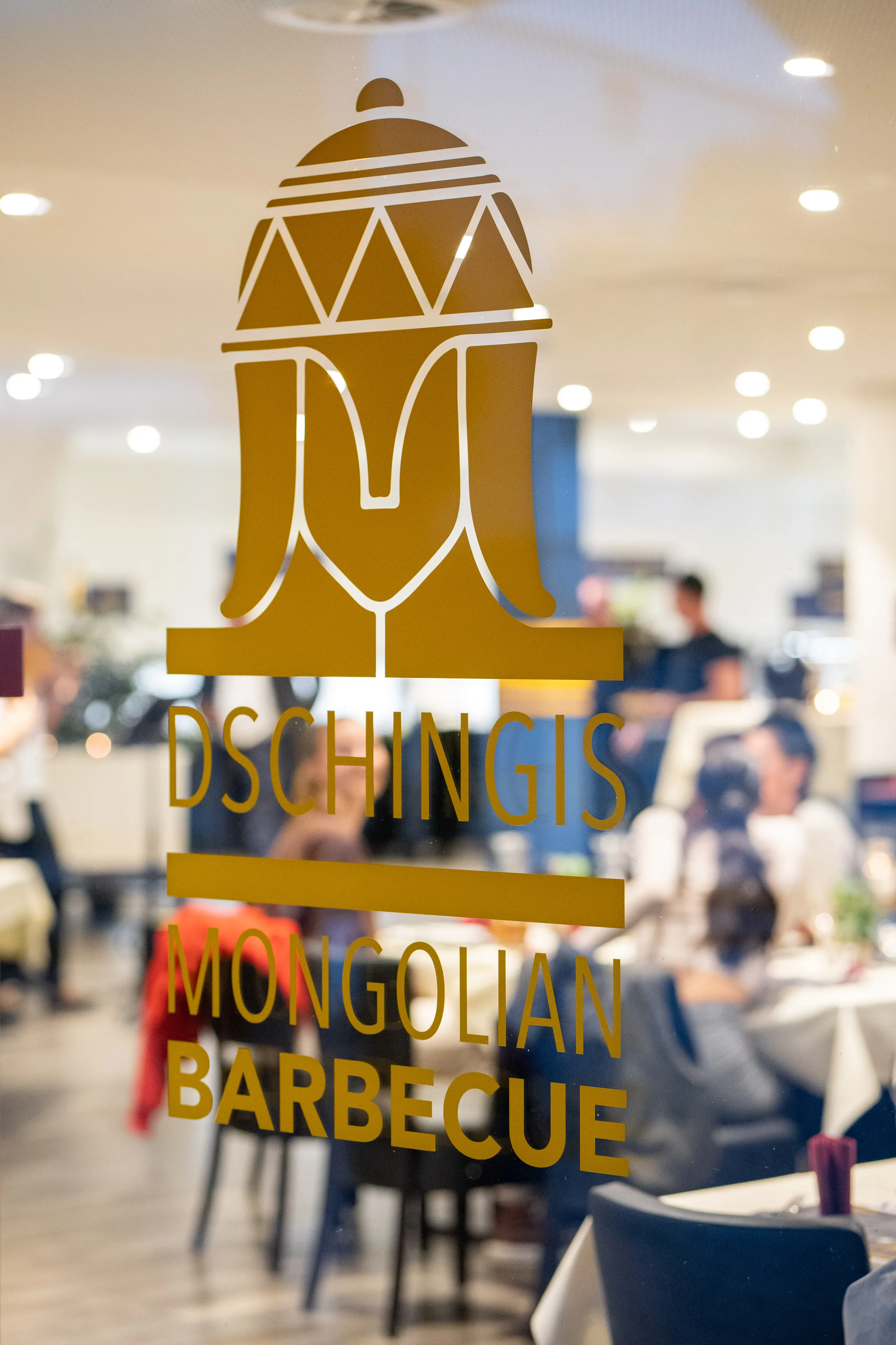 Dschingis-Logo an der Glastür, Gaststube im Hintergrund
